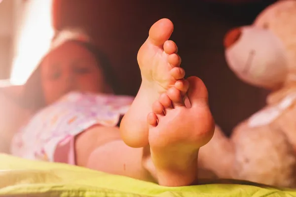 Uyku zamanı konsepti. Yatakta uyuyan tatlı bir kız çocuğu. Çıplak ayakla ilgilenmeye odaklan. Kapat..