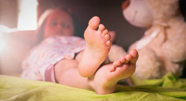 Küçük kız evde yatakta uyuyor. Yatak odasındaki yatağında çıplak ayakla çok güzel görünüyorsun. Uyku ve rahatlama konsepti. Yatay resim.