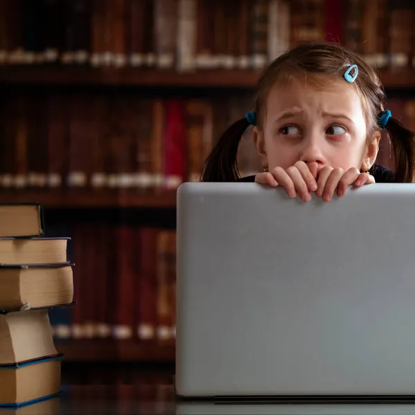 最大的图书馆是数字图书馆 年轻美丽的女孩坐在图书馆里 看着一堆书 却在用笔记本电脑学习 — 图库照片