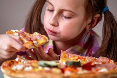 Genç ve çekici bir kız lezzetli bir dilim pizzanın tadını çıkarıyor. Yatay görüntü. Seçici odak.