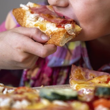Genç ve çekici bir kız lezzetli bir dilim pizzanın tadını çıkarıyor. Yatay resim.