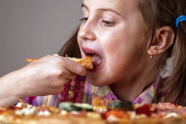 Yaklaş genç ve çekici kız bir dilim pizza yiyor.