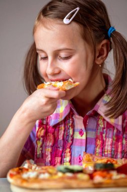 Genç ve çekici bir kız lezzetli bir dilim pepperonili pizzanın tadını çıkarıyor.