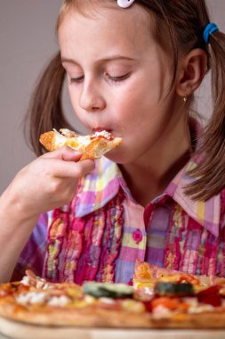Bir dilim pizza yiyen güzel ve çekici bir kız. Dikey resim.