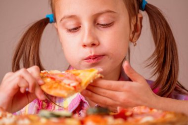 Lezzetli yemek. Pizzalı güzel bir genç kızın portresi. Mutlu çocuk yemek yerken eğleniyor..