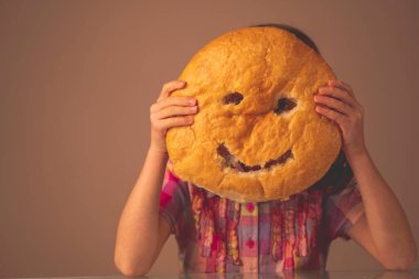 Ekmek gülüşü. Elinde ekmeğin etrafında gülümseyen genç bir kızın komik görüntüsü. Boşluğu kopyala.