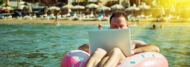 Her yerden ve her zaman çalışmak, uzak işgal konsepti. İş adamı serbest yazar, Tropikal Denizde şişme halka üzerine dizüstü bilgisayarla çalışıyor. Boşluğu kopyala.