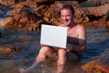 Deniz suyunda dizüstü bilgisayarla çalışan işadamının komik bir görüntüsü.. 