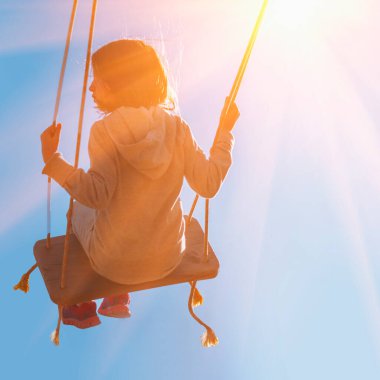 Dertsiz, mutlu genç bir kızın, mavi gökyüzüne karşı güneş ışığında sallanışı.. 