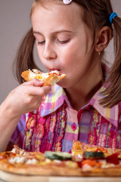 Close up young beautiful attractive girl eating a slice of pizza. Vertical image.