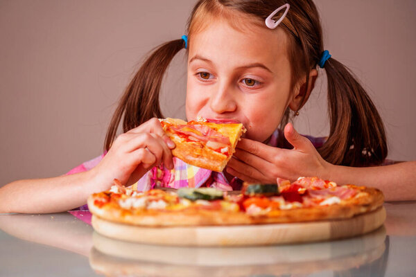 Young beautiful girl enjoys delicious slice of pizza. Horizontal image.