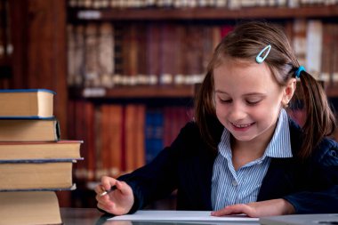 Kavramsal resim: öğrenme süreci. Kütüphanede dizüstü bilgisayarla öğrenen mutlu genç kızın portresi. Boşluğu kopyala.