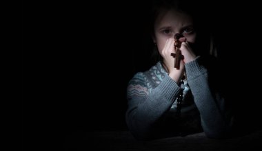 Genç ve güzel bir kız ahşap bir tespihle Tanrı 'ya dua ediyor. Çapraz sorgulamaya odaklan. Boşluğu kopyala.