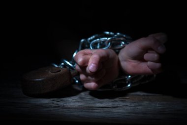 Siyah arka plana karşı zincirlenmiş ellerin kavramsal görüntüsü. Yatay resim.