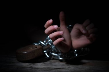 Siyah arka plana karşı zincirlenmiş ellerin kavramsal görüntüsü. El ve parmaklara odaklan.