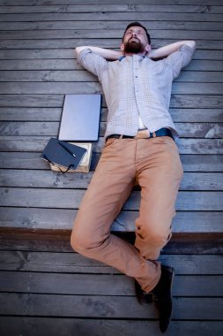 Ahşap zeminde yatan hippi işadamının en iyi görüntüsü. Adam işten dinleniyor. Dikey resim.