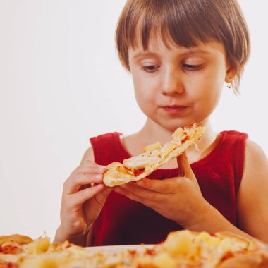 Güzel bir kızın portresi. Lezzetli bir dilim pizzanın tadını çıkarıyor. Bu tadı seviyor.