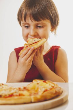 Güzel bir kız çocuğu lezzetli bir dilim pizzayı seviyor, bu tadı seviyor, iyi bir iştahı var. Dikey resim