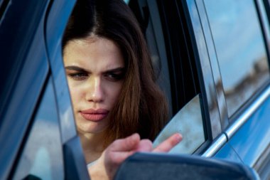 Agresif sürüş. Araba kullanırken orta parmak hareketi yapan kızgın bir kadın sürücü..