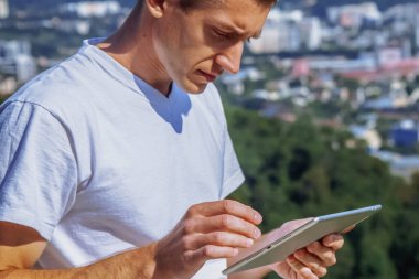 Her yerde ve her zaman çalışıyorum. Tablet kullanan yakışıklı bir iş adamı ve şehrin arka planında çalışıyor.. 