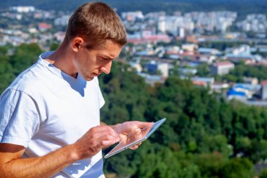 Her yerde ve her zaman çalışıyorum. Tablet kullanan ve şehrin arka planında uzaktan çalışan yakışıklı iş adamının portresi. Boşluğu kopyala.