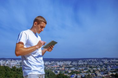 Şehrin arka planına karşı tablet kullanan yakışıklı iş adamı. Tasarım için alanı kopyala. Yatay resim.