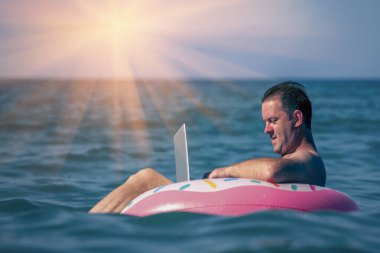 Her yerde ve her zaman çalışıyorum. İşadamı çalışıyor. Sudaki şişme halka üzerinde dizüstü bilgisayar kullanıyor..