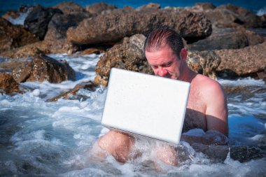 Her yerde ve her zaman çalışıyor. İş adamı deniz taşları üzerine bir dizüstü bilgisayarla çalışıyor.. 