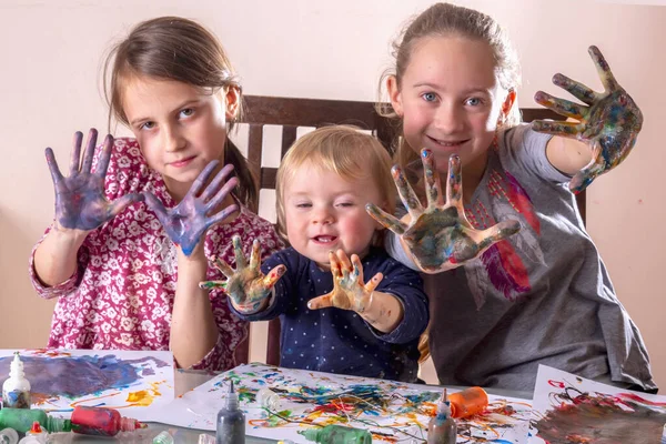 Renkli boyalı elleri olan mutlu çocuklar çiziyor ve eğleniyorlar. Tasasız mutlu çocukluk, öğrenme sanatı ve yaratıcılık.
