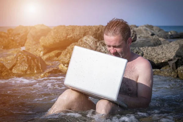 Deniz taşlarında dizüstü bilgisayarla çalışan bir iş adamı.. 