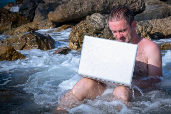 Her yerde ve her zaman çalışıyor. Deniz taşları üzerinde dizüstü bilgisayarla çalışan bir iş adamının portresi. Boşluğu kopyala.