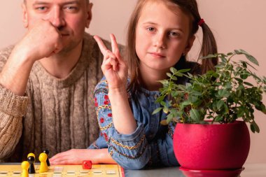 Küçük kız çocuğuyla eğlenmenin portresi. Masa oyunu oynuyorlar. Kızın gözlerine odaklan..