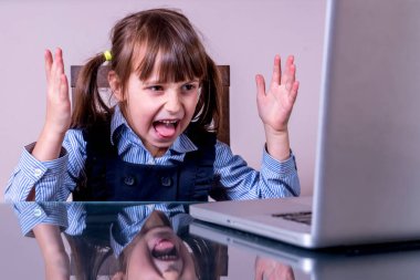 Çocuklar için çevrimiçi eğitim. Çok kızgın bir kızın yüz ifadesinin portresi bilgisayarla uzaktan öğreniliyor. Yatay resim.