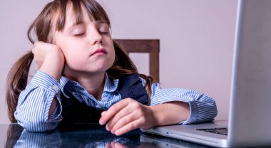 Çocuklar için çevrimiçi eğitim. Dizüstü bilgisayarı olan yorgun kız.