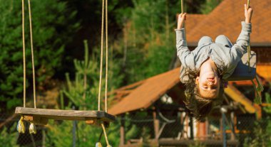 Genç güzel kız baş aşağı asılı ve dışarıda salıncakta eğleniyor.. 