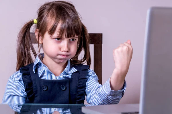 Çocuklar için çevrimiçi eğitim. Çok kızgın bir kız çocuğu bilgisayarla uzaktan öğreniyor.