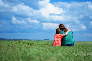 Two young girls sitting on the field of grass.