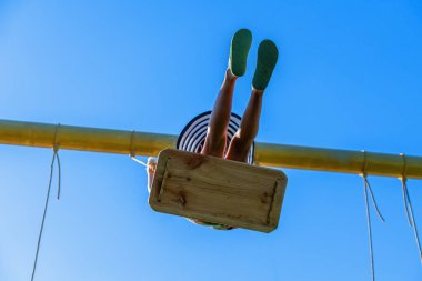 Mavi gökyüzüne karşı sallanan kaygısız, mutlu genç kız manzarası. Yaz tatili ve mutlu çocukluk konsepti.