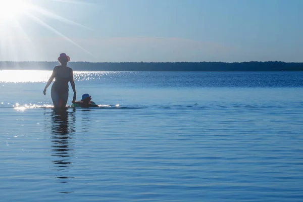 水の中の女性と子供のシルエット 美しい静かな海の風景です 夏休み 休息と旅行の概念 水平画像 スペースのコピー — ストック写真