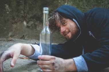Votka içen genç alkolik adamın portresi. Alkolizm, acı, acıma, evsizlik, bağımlılık kavramının sosyal problemi. Yatay resim.