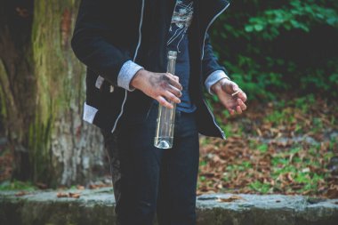 Elinde bir şişe votka ve sigarayla sarhoş bir gencin portresi. Alkolizm, acıma, umutsuzluk, bağımlılık kavramının sosyal problemi. Yatay resim.