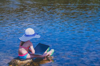 Küçük kız görüntülü konuşma yapıyor. Bilgisayarla uzaktan öğreniyor. Yaz tatili ve tatil konsepti, tabletle online çalışma, uzaktan öğrenme. Boşluğu kopyala.