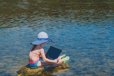 Küçük kız görüntülü konuşma yapıyor. Bilgisayarla uzaktan öğreniyor. Yaz tatili ve tatil konsepti, tabletle online çalışma, uzaktan öğrenme. Yatay görüntü. Boşluğu kopyala.