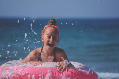 Güzel plajda şişme yüzüğü olan bir çocuk. Genç kız egzotik denizde yüzüyor. Okyanus çocuk tatili. Boşluğu kopyala.