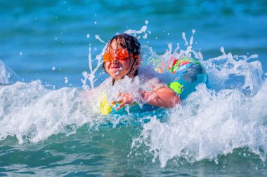 Şen şakrak bir halkayla gezen neşeli kız çocuğu. Seyahat, sağlıklı yaşam tarzı, yüzme aktiviteleri ve yaz tatili konsepti..