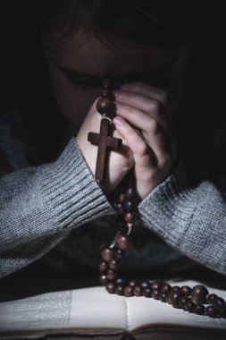 Tanrı 'ya dua et. Genç kızın yakın portresi. Tespihle dua et ve İncil oku. Dikey resim.