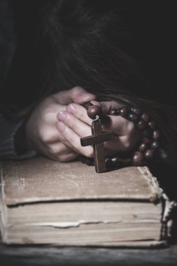 Tanrı 'ya dua et. Genç kız tespihle dua edip İncil okuyor. Dikey resim.