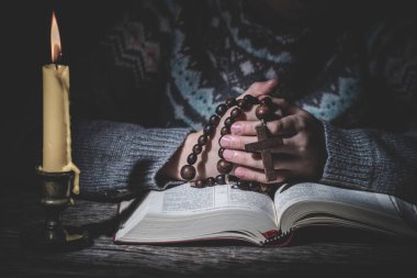 Tanrı 'ya dua et. Genç kız tespihle dua edip İncil okuyor. İnanç kavramı. 