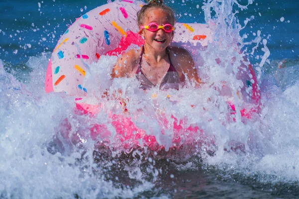 Egzotik denizde yüzen şişme yüzüklü çok mutlu bir genç kız. Çocuklar için okyanus tatili.