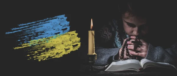 Pray for Ukraine. Save Ukraine from Russia. Young girl pray with rosary and reading the Bible.